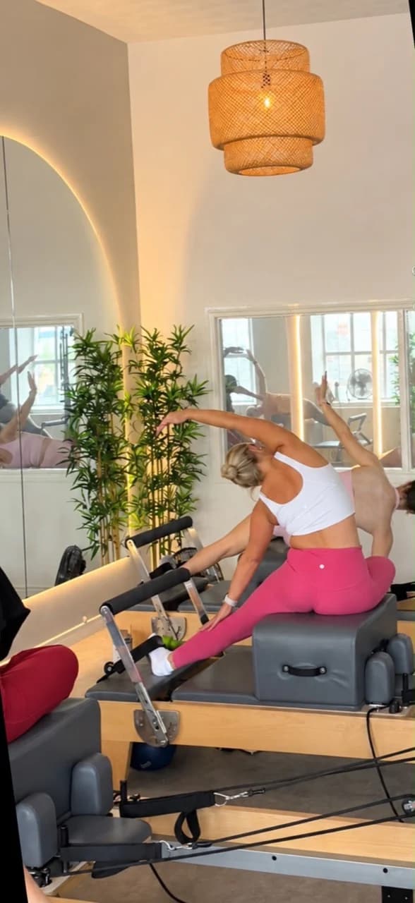 A client stretching sideways over a reformer box during a group class in the Ebrington studio